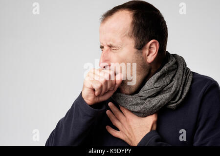 Mature man in scarf is ill from colds or pneumonia. Suffering from flu virus. Stock Photo