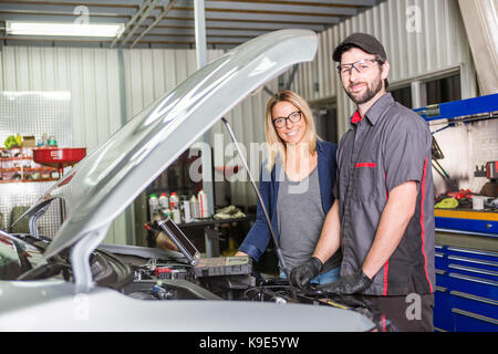 An auto mechanic and female customer in garage Stock Photo