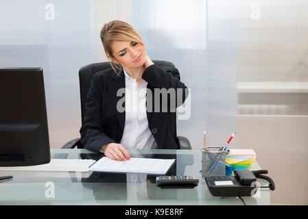 Portrait Of Young Businesswoman Suffering From Neckache In Office Stock Photo