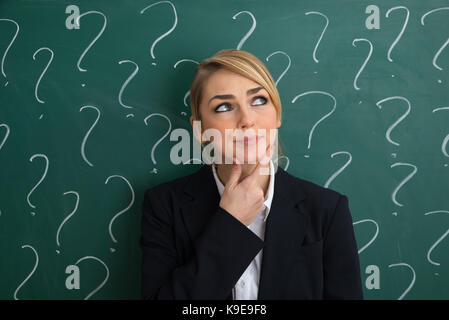Thoughtful Businesswoman In Front Of Chalkboard With Question Mark Sign Stock Photo