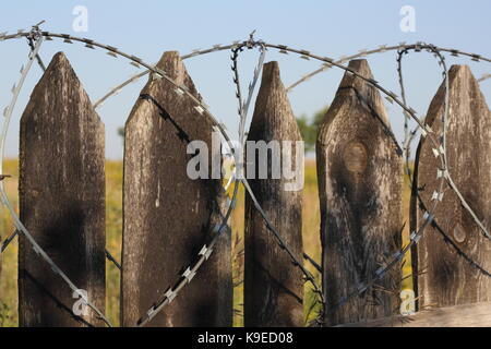 Old wooden fence with barbed wire closeup photo Stock Photo