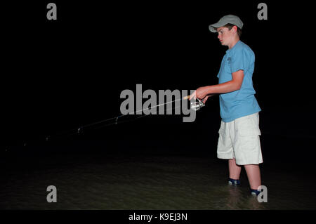 A young boy wad fishing at night on the Texas Gulf Coast near Port Aransas Stock Photo