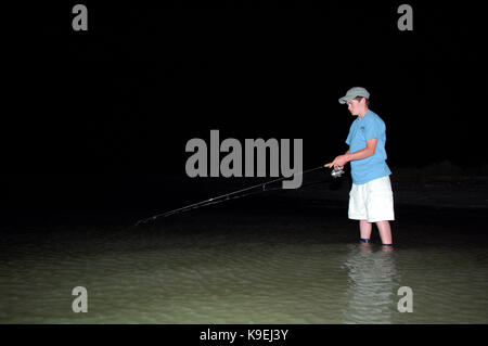 A young boy wad fishing at night on the Texas Gulf Coast near Port Aransas Stock Photo