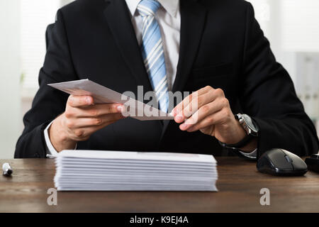 Close-up Of Businessman With Envelopes At Desk In Workplace Stock Photo