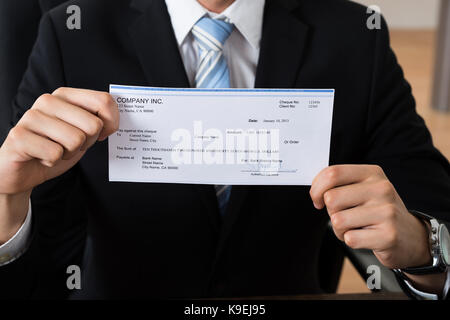 Close-up Of Businessman Showing Signed Cheque In Office Stock Photo