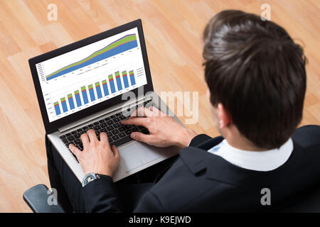 High Angle View Of Young Businessman Checking Financial Report On Laptop Stock Photo