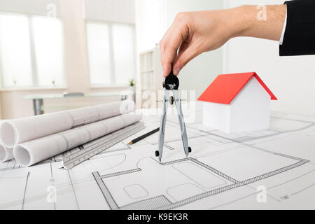 Close-up Of Male Architect Hands Holding Compass On Blueprint Stock Photo
