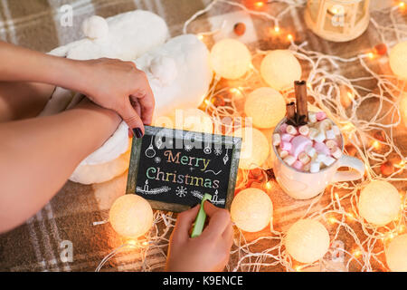 Woman writing greeting card with text Merry Christmas Stock Photo