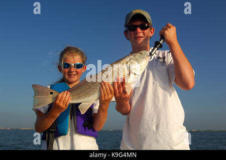 A young boy and girl with a redfish or red drum caught while fishing near Port Aransas Texas Stock Photo