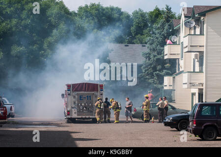 Vadnais Heights, Minnesota.  Firefighters put on their equipment  to put out a dumpster that is on fire in the apartment complex. Stock Photo