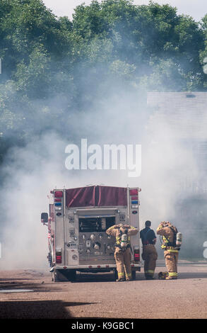 Vadnais Heights, Minnesota.  Firefighters put on their equipment  to put out a dumpster that is on fire in the apartment complex. Stock Photo