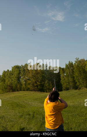 Balsam Lake, Wisconsin.  Skeet shooting. 12 gauge shotgun. 13 year old teenager hitting the clay target in the air. Stock Photo