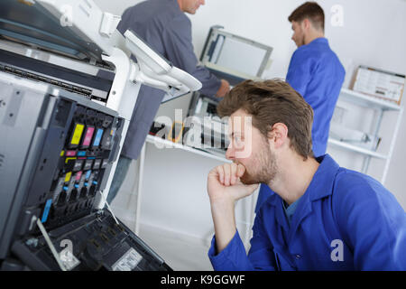young efficient engineer working on a printer and adjusting components Stock Photo