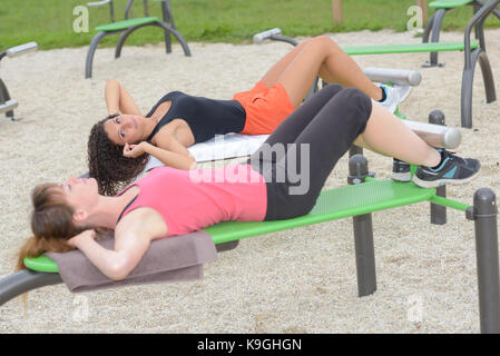 two young women doing crunches in the park Stock Photo