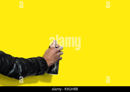 hand with a balloon for graffiti against a pure yellow of the wall. Photo copy space. Stock Photo