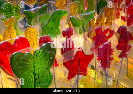 Sweets on counter at candy shop. Multi-colored sucking candies in the form of various figurines on a stick. Stock Photo