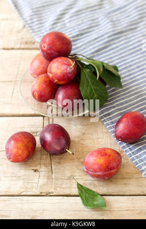 Plums in a plate on a wooden table, rustic style, selective focus. Stock Photo