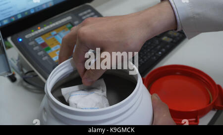 https://l450v.alamy.com/450v/k9gmck/chemical-scientist-opening-white-unlabeled-plastic-tank-canister-with-k9gmck.jpg