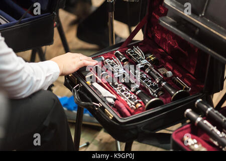 music, performance, equipment concept. arm of player touching tenderly disassembled matt black clarinet, kept in small special case with gorgeous velv Stock Photo