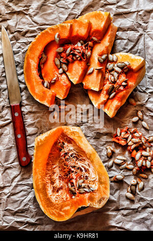Pieces of ripe pumpkin and seeds on a background of crumpled packing paper. Top view, closeup Stock Photo