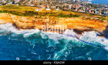 Wave break of endless Pacific oceanic waves hitting and eroding sandstone rocky plato of Australian continent around MacQuarie lighthouse in Sydney. Stock Photo