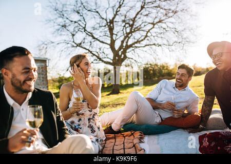 Multiracial group of friends sitting outdoors and smiling. Young people relaxing at outdoors party on a summer day. Stock Photo