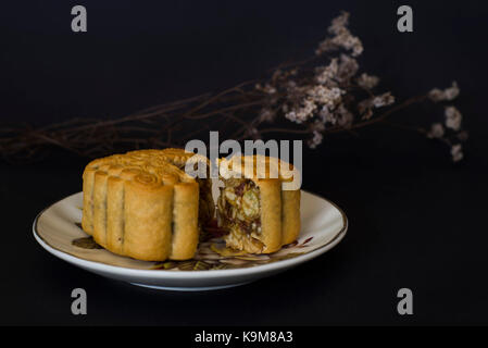 Chinese Traditional Mid Autumn Festival moon cakes with mixed nuts filling on black background Stock Photo