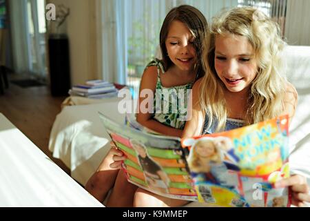 Two girls reading teen magazine Stock Photo