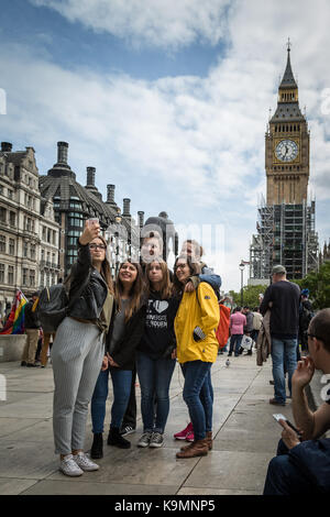 Tourists take selfie photos in Parliament Square in front of Big Ben cladded in scaffolding. Westminster, London, UK. Stock Photo