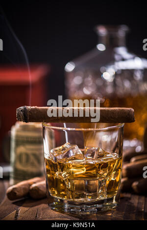 Glass of Scotch or Cognac over ice cubes and Cigar on wooden table Stock Photo