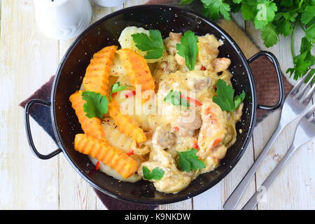 Chicken with mushrooms in a creamy sauce with fried sweet potato in a black metal bowl on a wooden background. Healthy eating concept. Mediterranean l Stock Photo