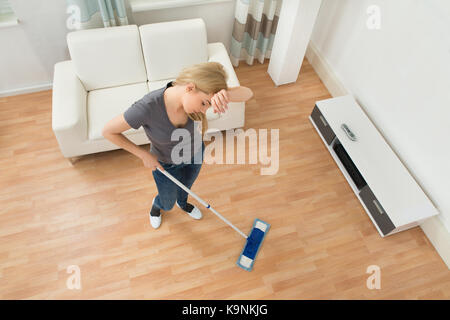 High Angle View Of Tired Woman With Mop In Living Room Stock Photo