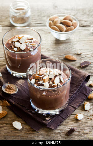 Chocolate Mousse topped with Almond in glasses over wooden background close up - delicious homemade Raw Vegan Chocolate Pudding with Nuts and Carob po Stock Photo