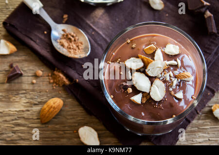 Chocolate Mousse topped with Almond in glasses over wooden background close up - delicious homemade Raw Vegan Chocolate Pudding with Nuts and Carob po Stock Photo