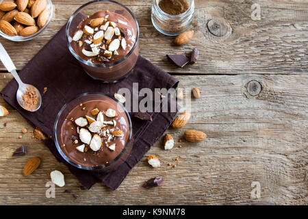 Chocolate Mousse topped with Almond in glasses over wooden background close up - delicious homemade Raw Vegan Chocolate Pudding with Nuts and Carob po Stock Photo