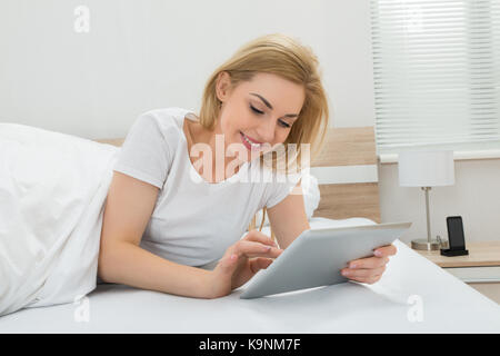 Young Happy Woman In Bed Using Digital Tablet Stock Photo