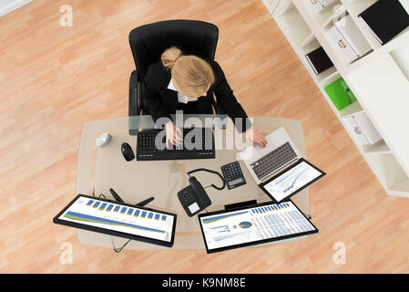 Young Businesswoman Analyzing Financial Statistics On Computer Screen In Office Stock Photo