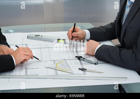 Close-up Of Two Businessman Working On Blueprints In The Office Stock Photo