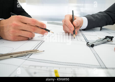 Close-up Of Two Architects Planning Project On Blueprint Stock Photo