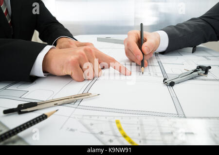 Close-up Of Two Architects Planning Project On Blueprint Stock Photo