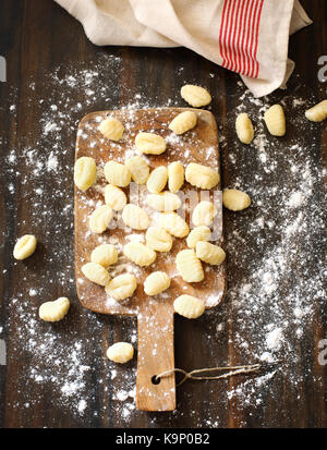 Uncooked homemade potato gnocchi on wooden background, top view Stock Photo