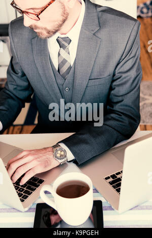Looking down at very handsome business professional sharply dressed using laptop and drinking coffee. Stock Photo