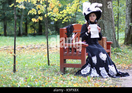 girl in retro dress past century read letter on the bench Stock Photo