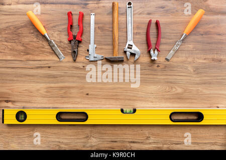Old construction tools pliers, calipers, hammer, adjustable wrench, chisel, nippersare, llevel ocated vertically on the wooden floor close-up Stock Photo