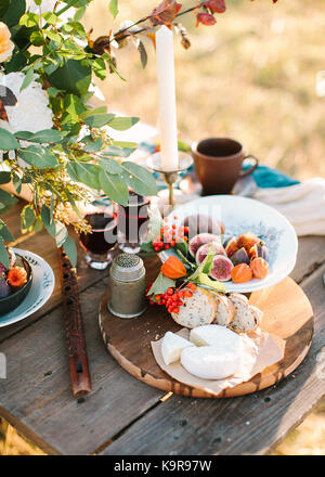 freshness, picnic, holidays concept. romantic dinner outdoors with fresh bread and cheese, fruits and wine in sparkling glasses, nearby with food there is wooden flute Stock Photo