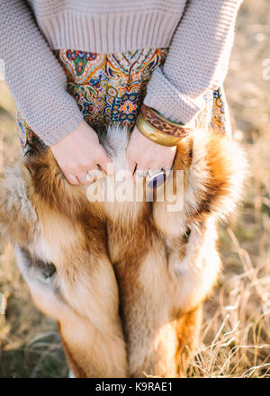 boho style, fall, freedom concept. charming girl dressed in skirt with ornaments of autumnal shades and smoky sweater holding red fox skin in small arms with original accessories Stock Photo