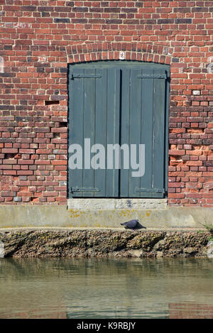 a pair of green painted shabby chic style doors on old riverside warehouse on the banks of the river Medina on the Isle of Wight..access from river. Stock Photo