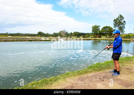 Woman fishing at a barramundi farm, Mossman, Far North Queensland, FNQ, QLD, Australia Stock Photo