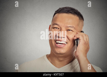 Closeup portrait headshot handsome young man student happy guy excited employee, using cell phone, smiling, having pleasant conversation isolated grey Stock Photo