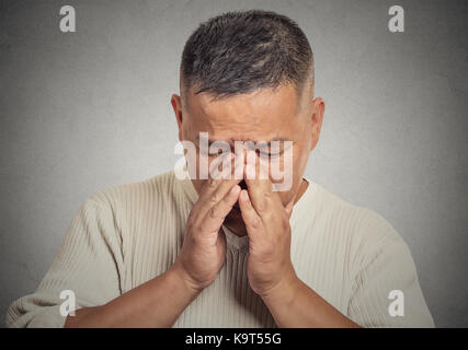 Headshot portrait of a sad young man looking down isolated on grey wall background Stock Photo